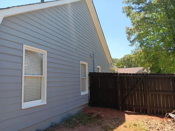 Gray lap siding with white window trim beside a dark stained wood privacy fence