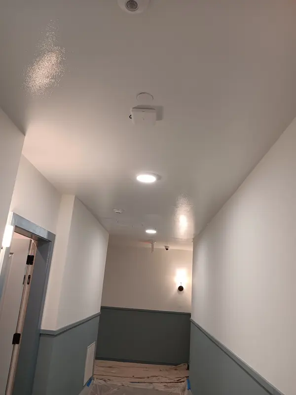 Corridor with dark gray wainscot and white walls under recessed ceiling lights