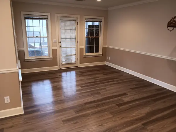 Empty room with new wood-look plank flooring, two-tone beige walls and a chair rail