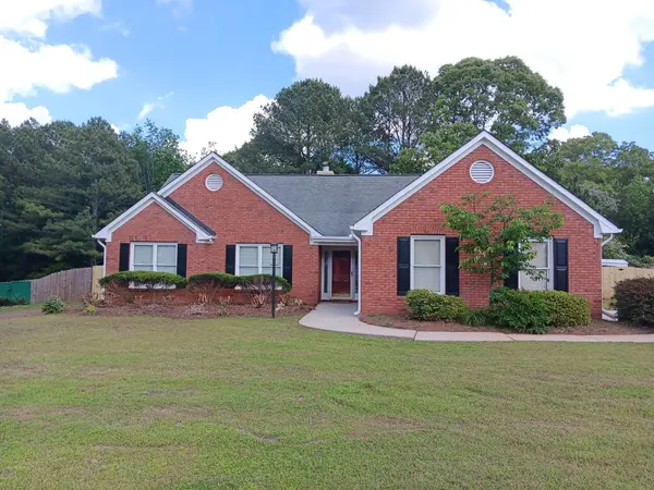 Red brick ranch home with black shutters and white trim under a blue sky