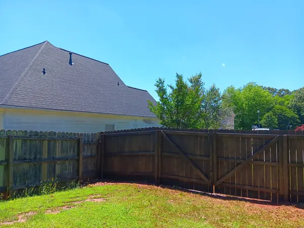 Dark stained wood privacy fence with a double gate around a grassy back yard