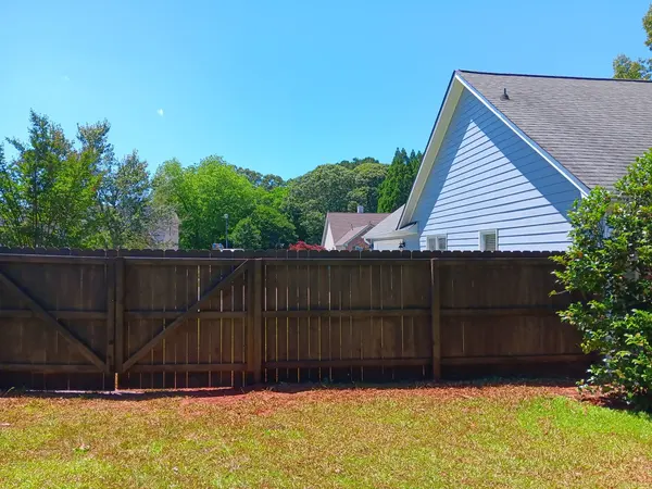 Dark stained wood privacy fence with a braced gate along a back yard