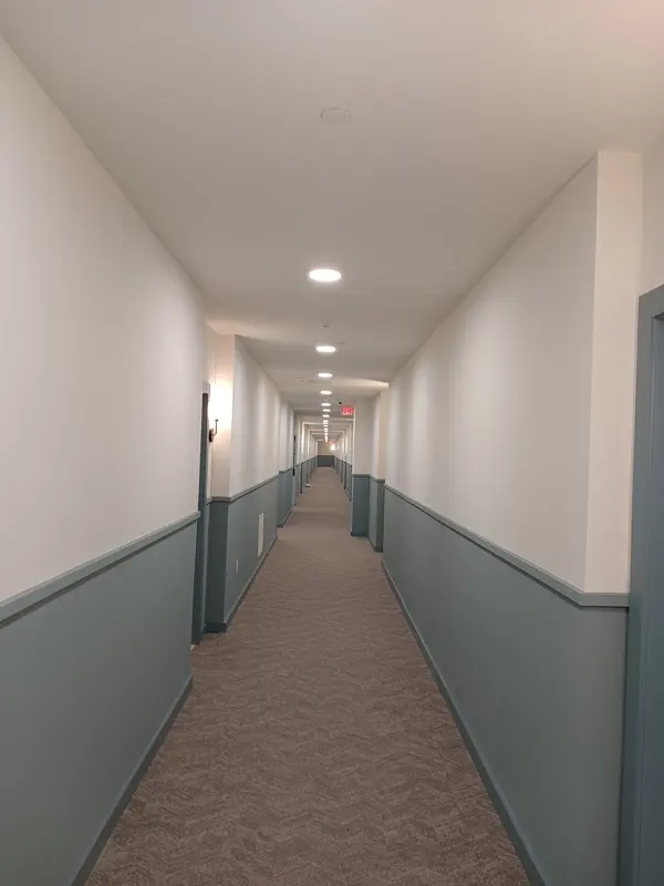 Finished corridor with gray wainscot, white walls, wall sconces and new carpet