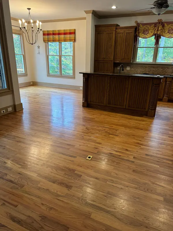 Honey-toned hardwood running through an open living area to a dark wood kitchen island