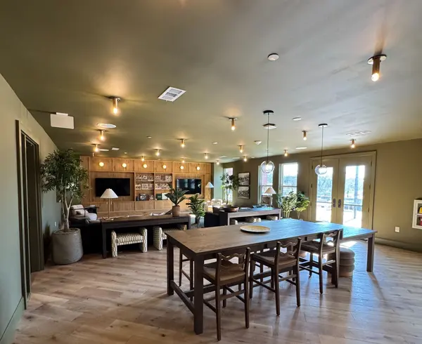 Large clubroom with olive walls, track lighting, a long dining table and wood built-ins