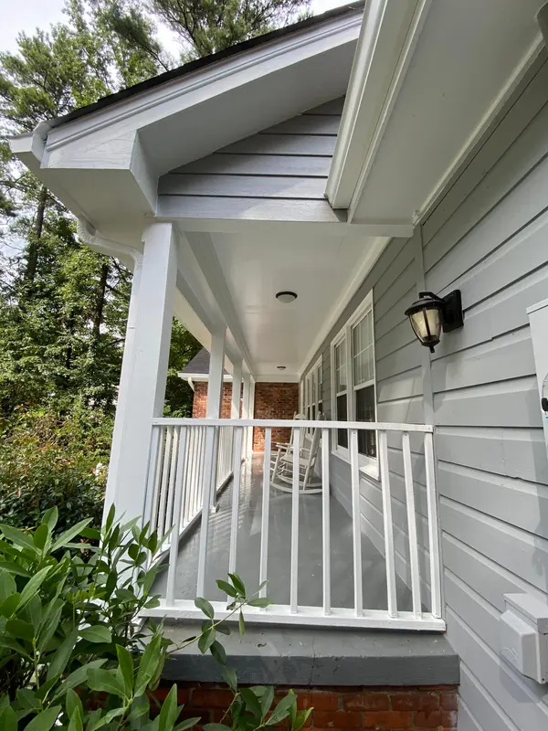 Covered side porch with gray lap siding, white posts and a white railing