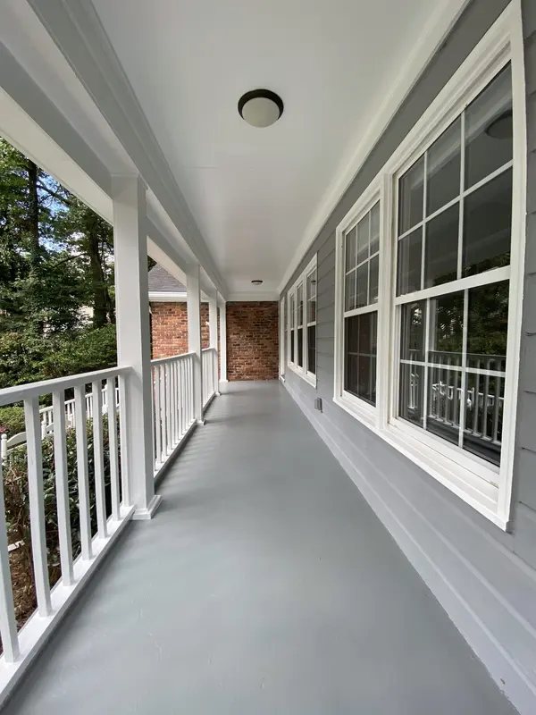 Freshly painted front porch with a gray floor, white railing and white window trim