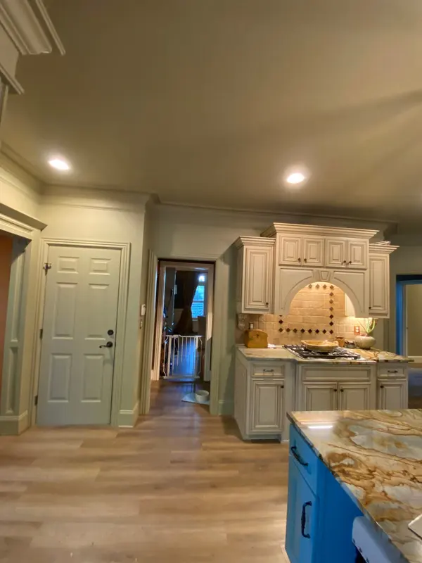 Kitchen with cream glazed cabinets, a tiled range hood alcove and a blue island with granite top