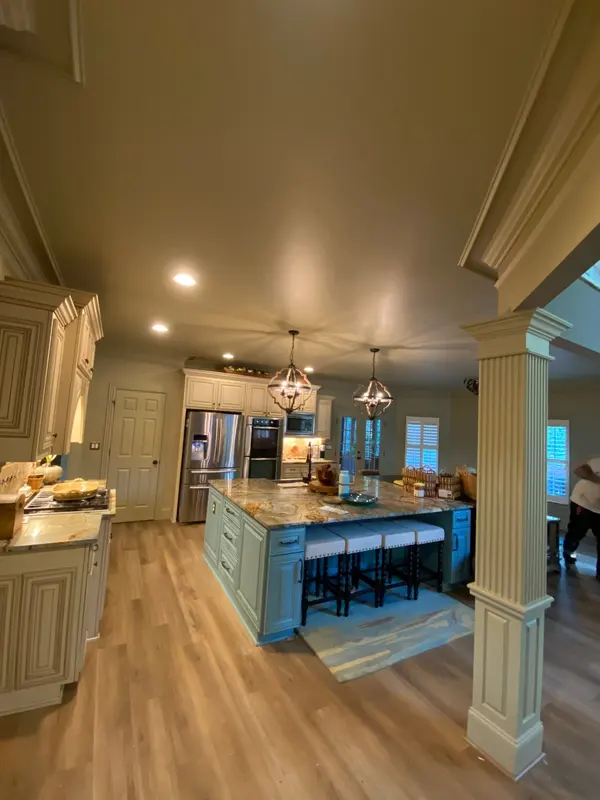 Kitchen with cream cabinetry and a blue-painted island under pendant lights