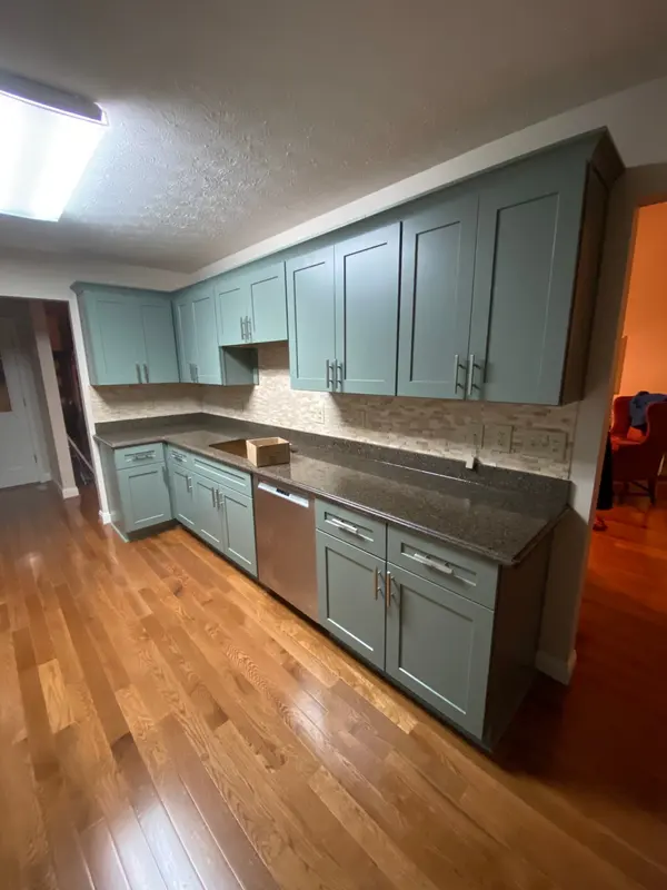 Kitchen with sage green painted shaker cabinets, dark granite tops and oak flooring