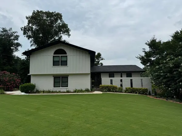 White painted brick and board-and-batten home with an arched window and black trim