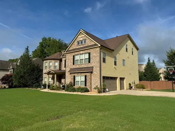 Two-story brick and pale yellow siding home with a side garage across a large lawn