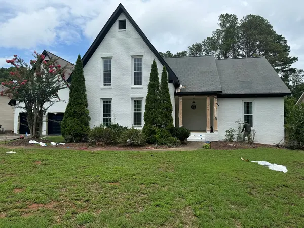 White painted brick front with black gable trim and drop cloths on the lawn