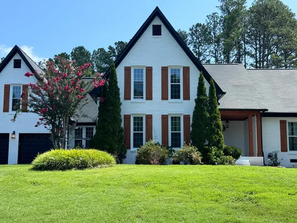 White painted brick home with cedar-tone shutters, black gable trim and a crepe myrtle