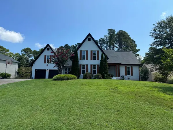 White painted brick home with cedar shutters seen across a wide lawn