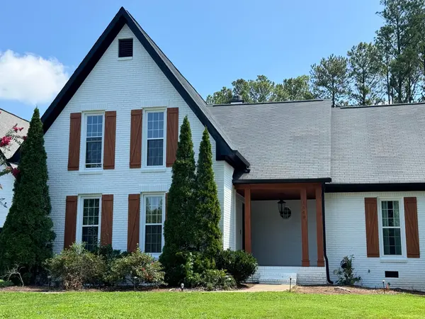 White painted brick home with rust-red shutters and a dark roof