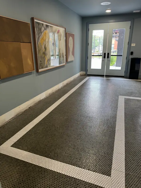 Lobby with blue-gray walls, framed art and a penny tile floor with a white border
