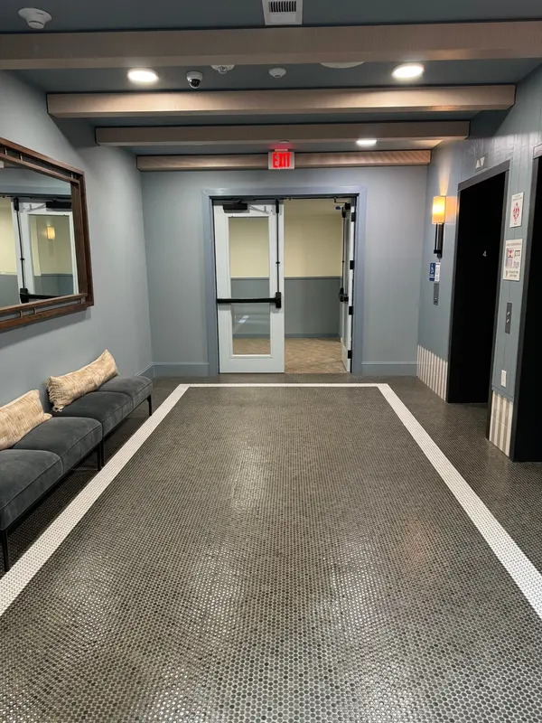 Apartment elevator lobby with blue-gray walls, a bench and dark wood ceiling beams