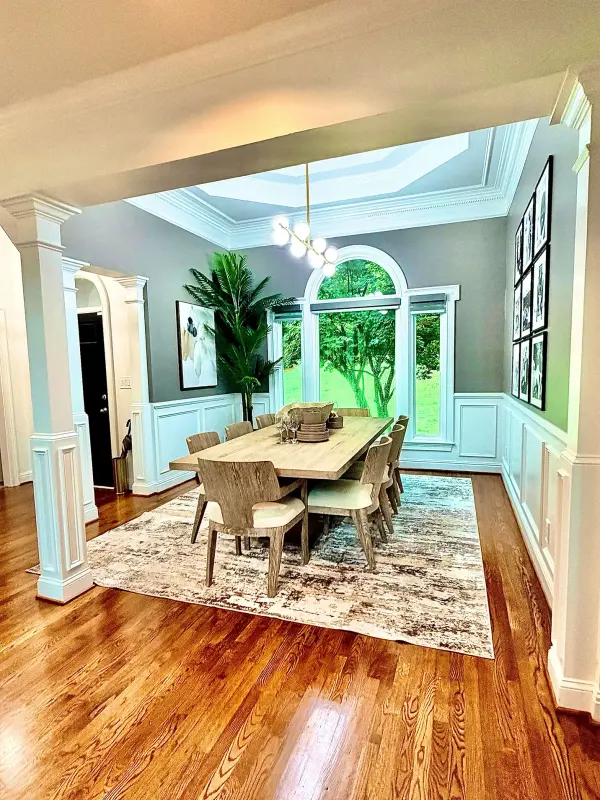 Dining room with blue-gray walls, white wainscoting, a tray ceiling and refinished floors