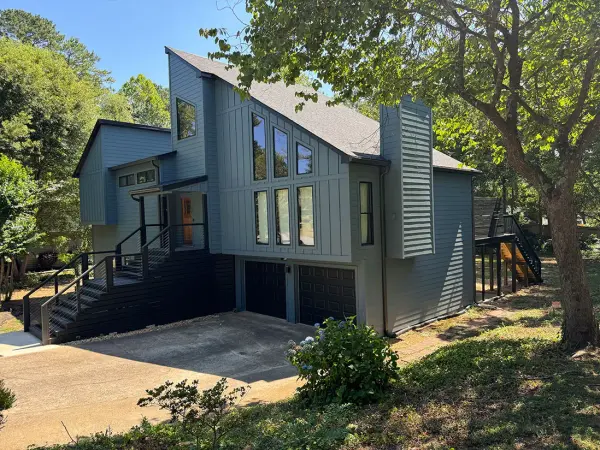 Contemporary home painted slate blue with dark trim, tall windows and black stair railings