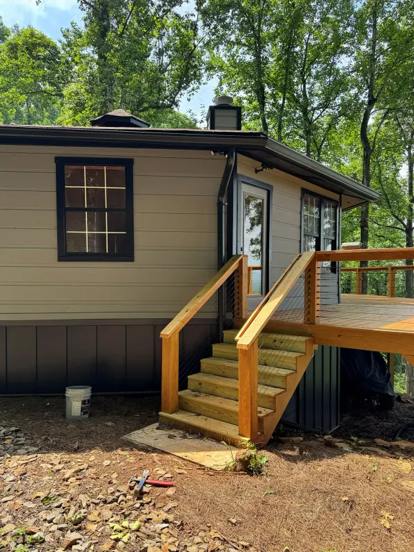 New pressure-treated deck stair and railing at the back of a tan sided home
