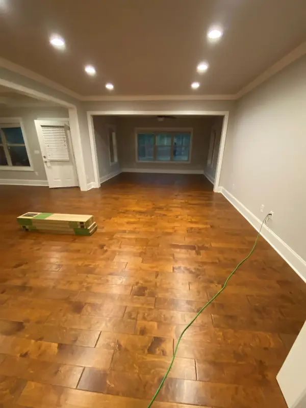 Empty room with new hand-scraped hardwood flooring and white baseboards