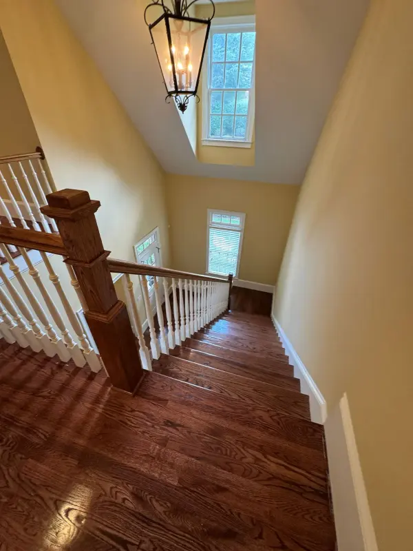 Upstairs landing with glossy hardwood floors, a white balustrade and pale yellow walls