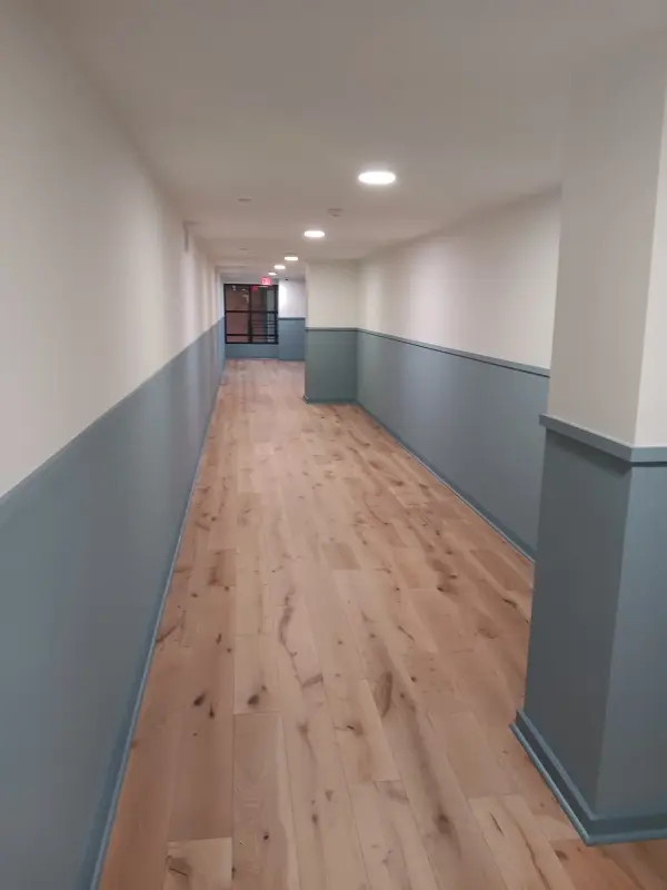 Long corridor with blue-gray wainscot paint and new light oak flooring