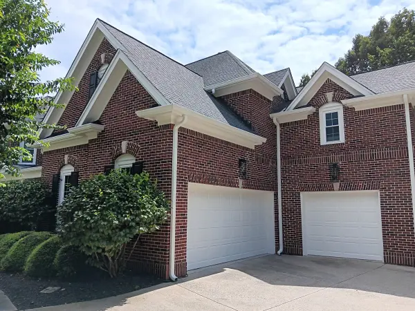 Red brick two-story home with white trim, gables and a double garage