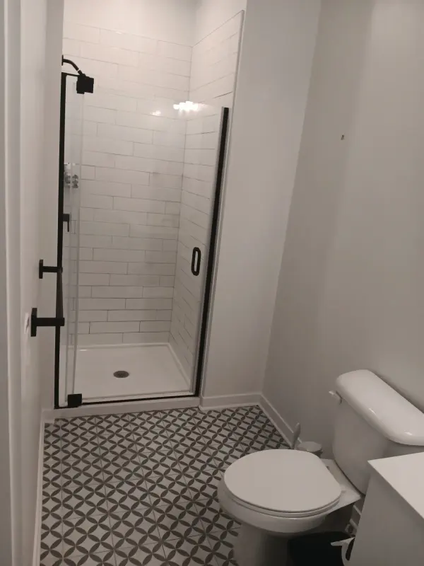 Bathroom with a white subway tile shower, black frame glass door and patterned gray tile floor