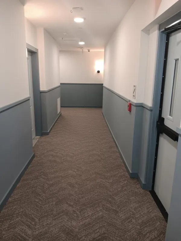 Corridor with gray wainscot paint, white walls and patterned carpet