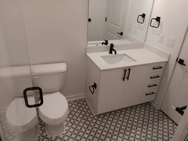 Bathroom with a white vanity, matte black hardware and a patterned gray and white floor tile