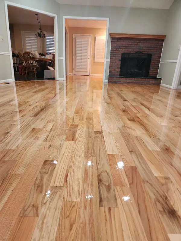 Glossy refinished natural oak floor running to a brick fireplace