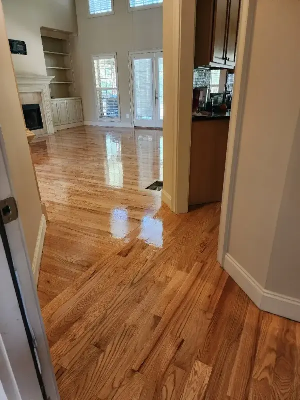 Refinished oak floor with a glossy finish running past a doorway into a family room