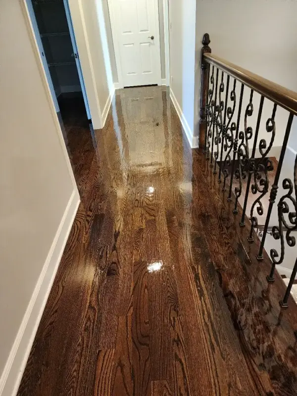 Upstairs hall with glossy dark stained hardwood and a wrought iron railing