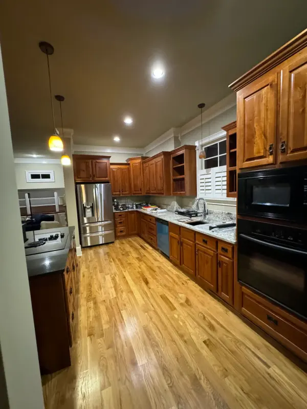 Long kitchen with cherry cabinets, stainless appliances and freshly refinished oak floors