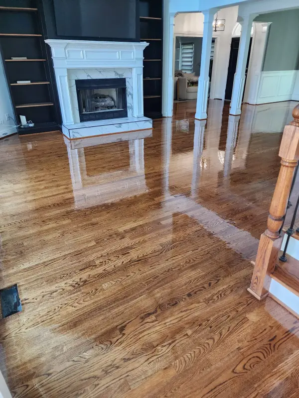 Living room with glossy refinished oak floors, a white marble fireplace and white columns