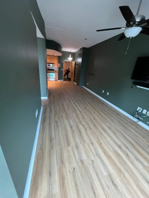 Long open room with deep green walls and new light wood-look plank flooring