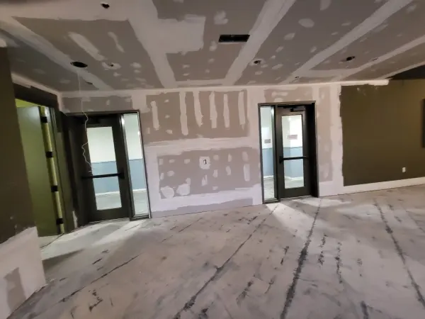 Commercial room with new drywall taped and mudded around two glass doors