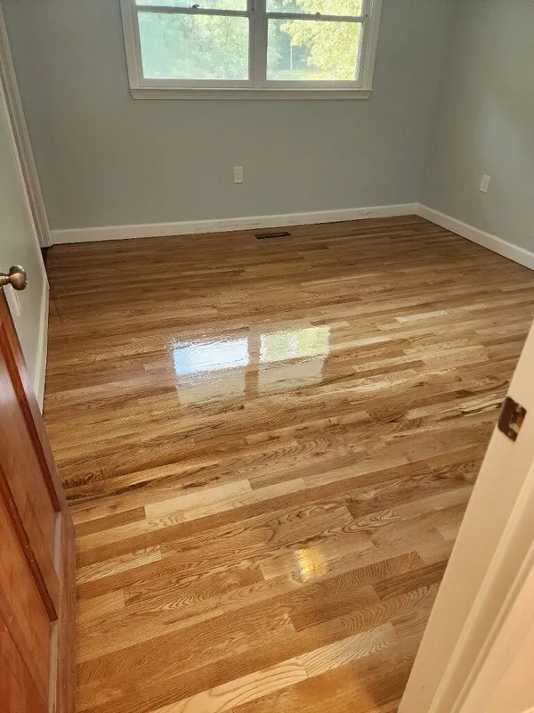 Finished red oak floor reflecting the window light, pale gray-blue walls and white trim