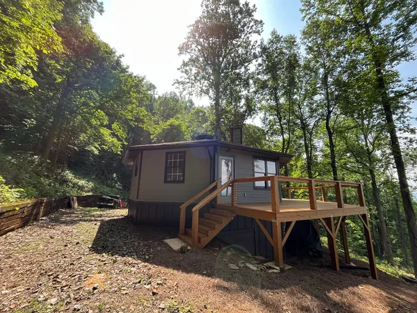 Small home on a wooded slope with a new raised wood deck and stair
