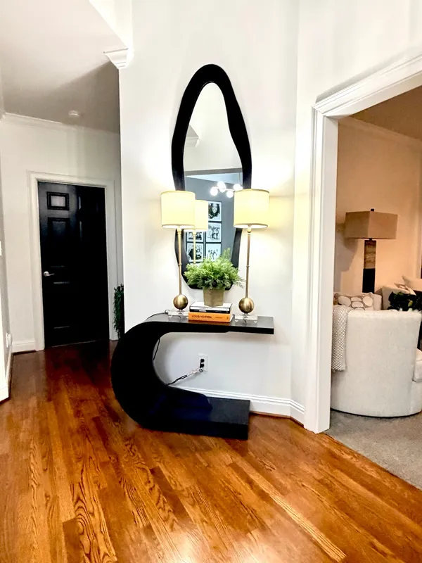 Entry with a black door and a round mirror over a console table, dark hardwood through to a sitting room