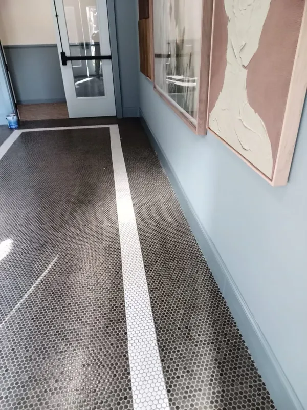 Penny-round mosaic corridor floor with an inlaid white stripe, pale blue walls