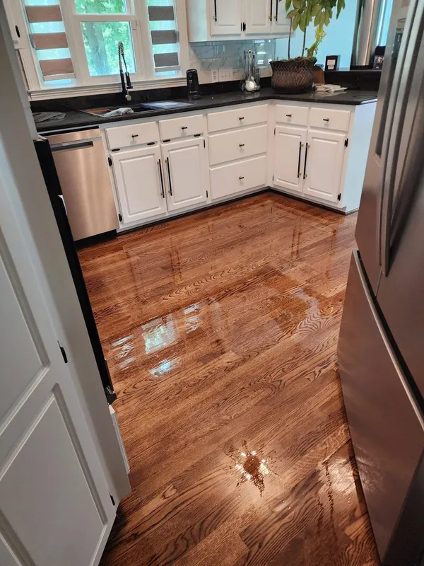 White wall cabinets and dark counters above a freshly refinished hardwood floor