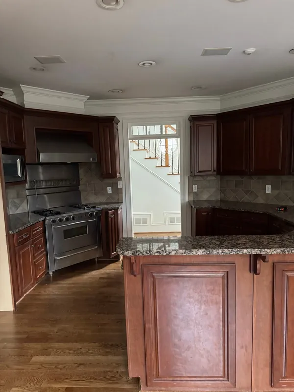 Cherry kitchen with a stainless range and hood, granite tops and a raised island
