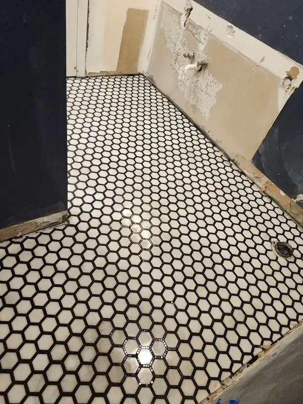 New black and white hexagon mosaic floor in a small room with walls stripped back