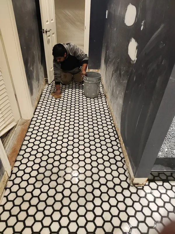 Hex mosaic floor being cleaned off by hand, surrounding walls in dark fresh paint