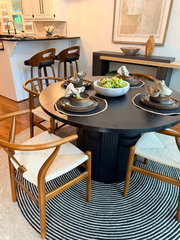 Dining area with a dark round table against pale walls and oak flooring