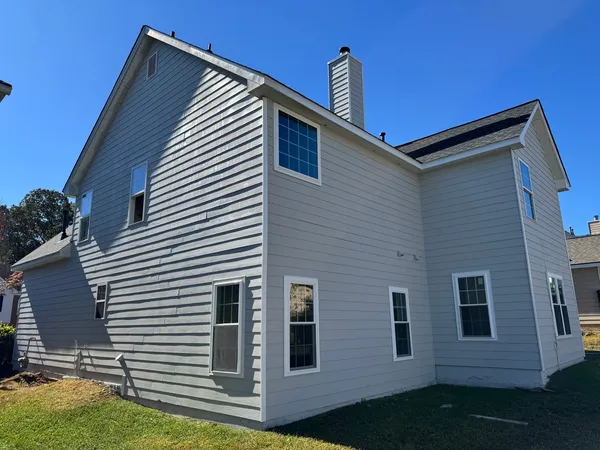Gray lap siding with white window trim on the side of a two-story home