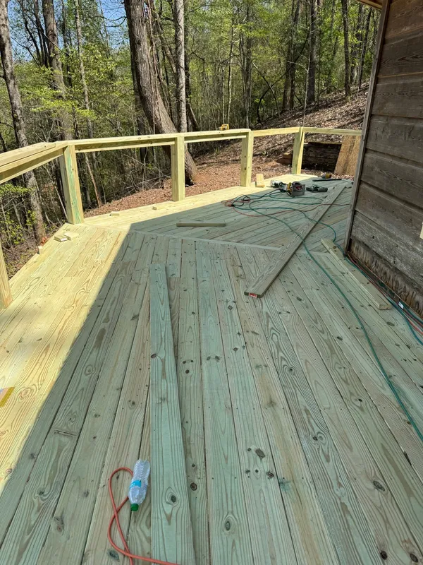 Green pressure-treated deck part way through boarding, offcuts and cord still out